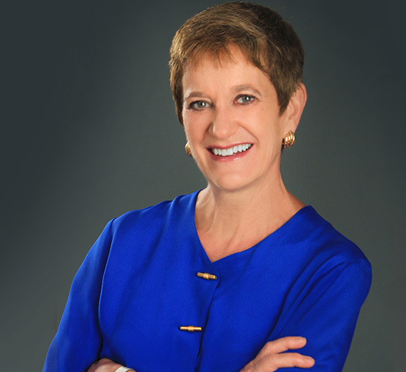 Man leans against brick wall with cherry blossom tree behind it.