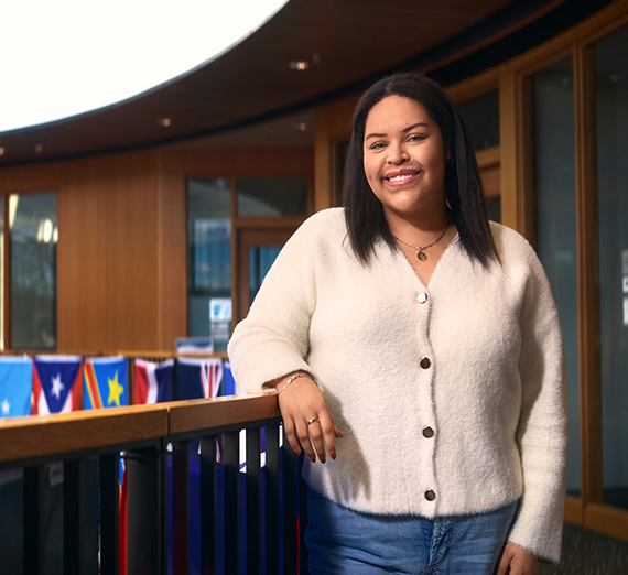 A woman stands next to several kayaks